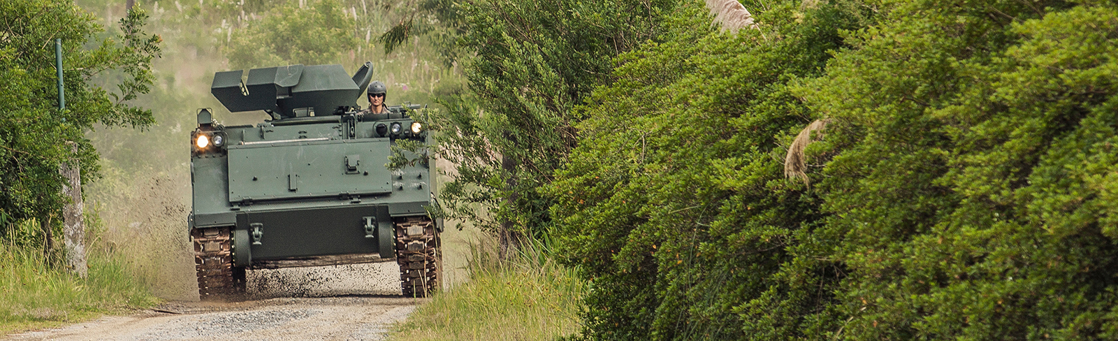 M113 Vehicle driving on dirt road in forest