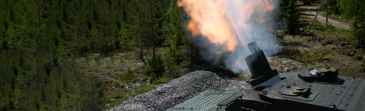 A CV90 Mjölner firing above a forest