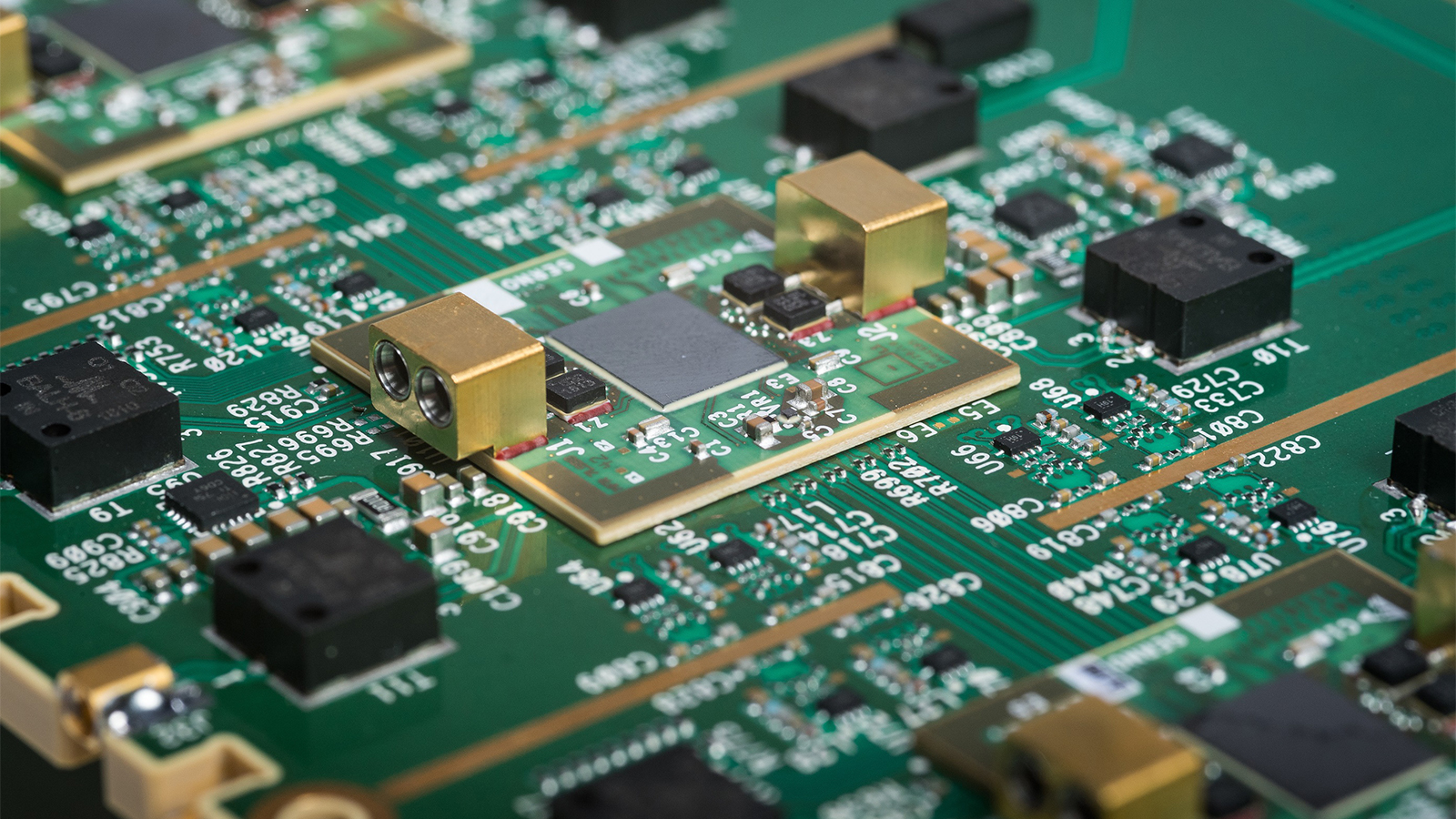 BAE Systems electrical engineers reviewing new defense electronics designs in front of new processing equipment in development