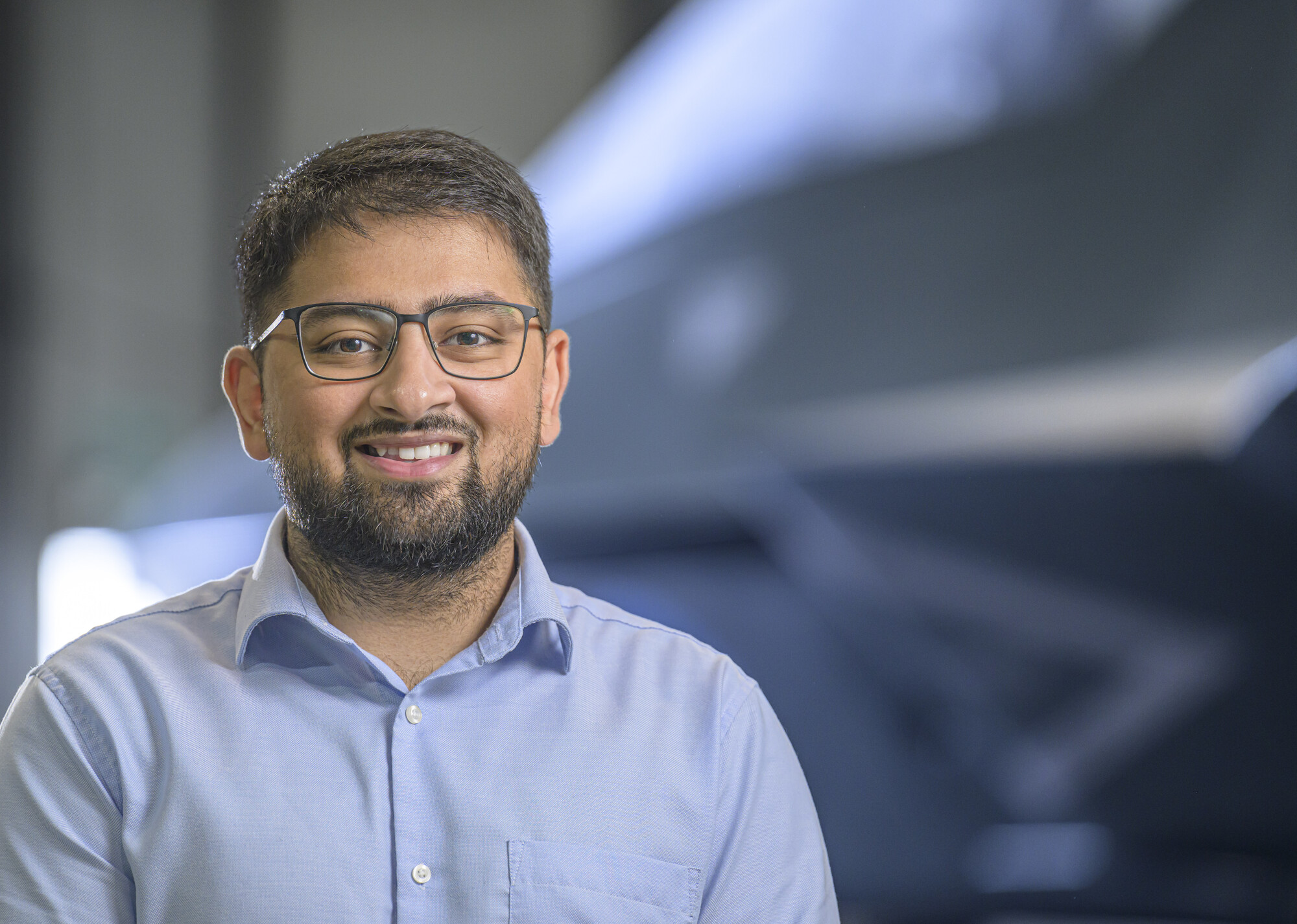 Yamin looking at the camera smiling with the Tempest concept model in the background
