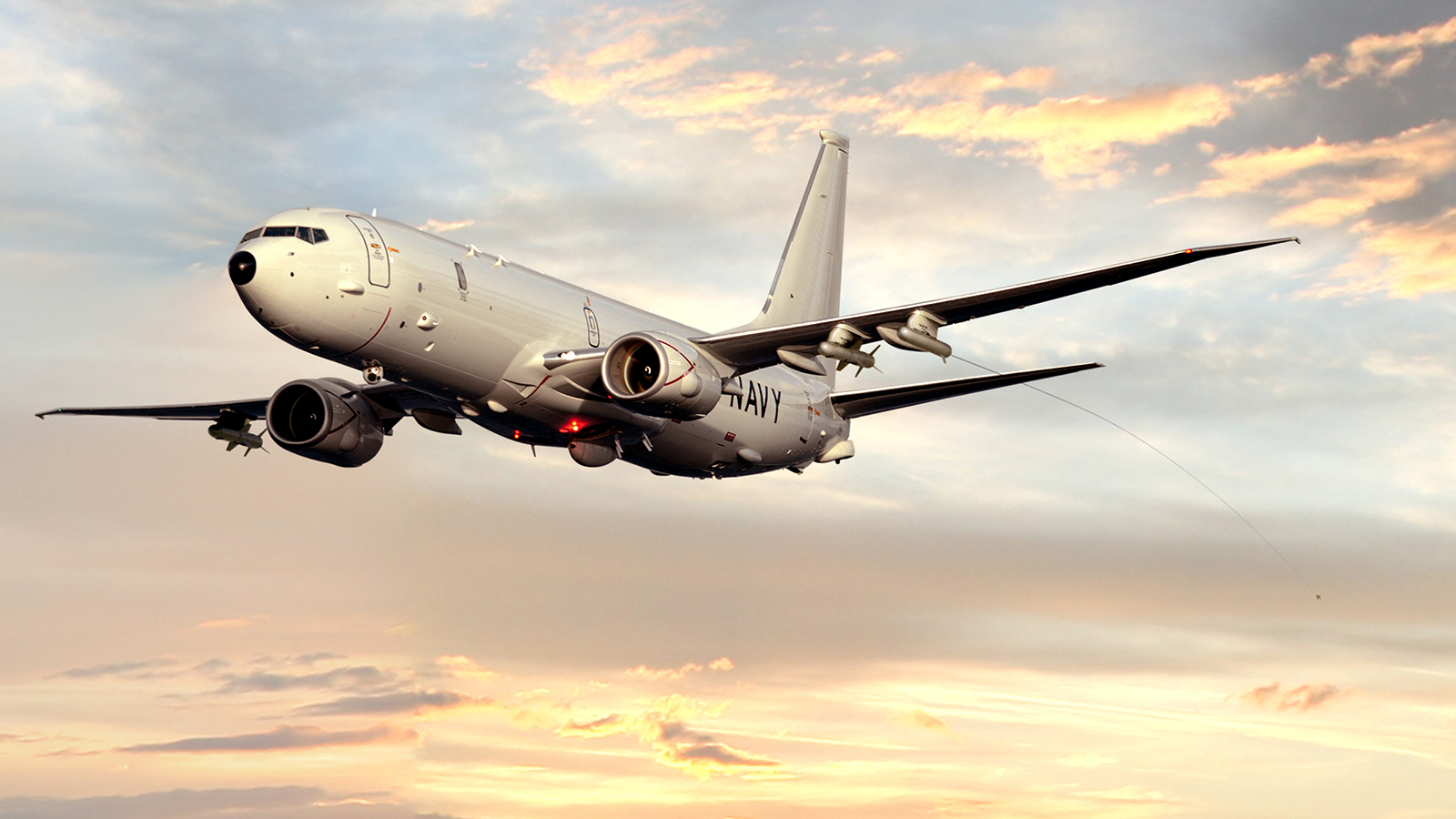 A U.S. Navy P8-A Poseidon aircraft flying at dusk with one of several possible pylons deployed behind it to detect and counter threats as part of a portable BAE Systems survivability pod system. 