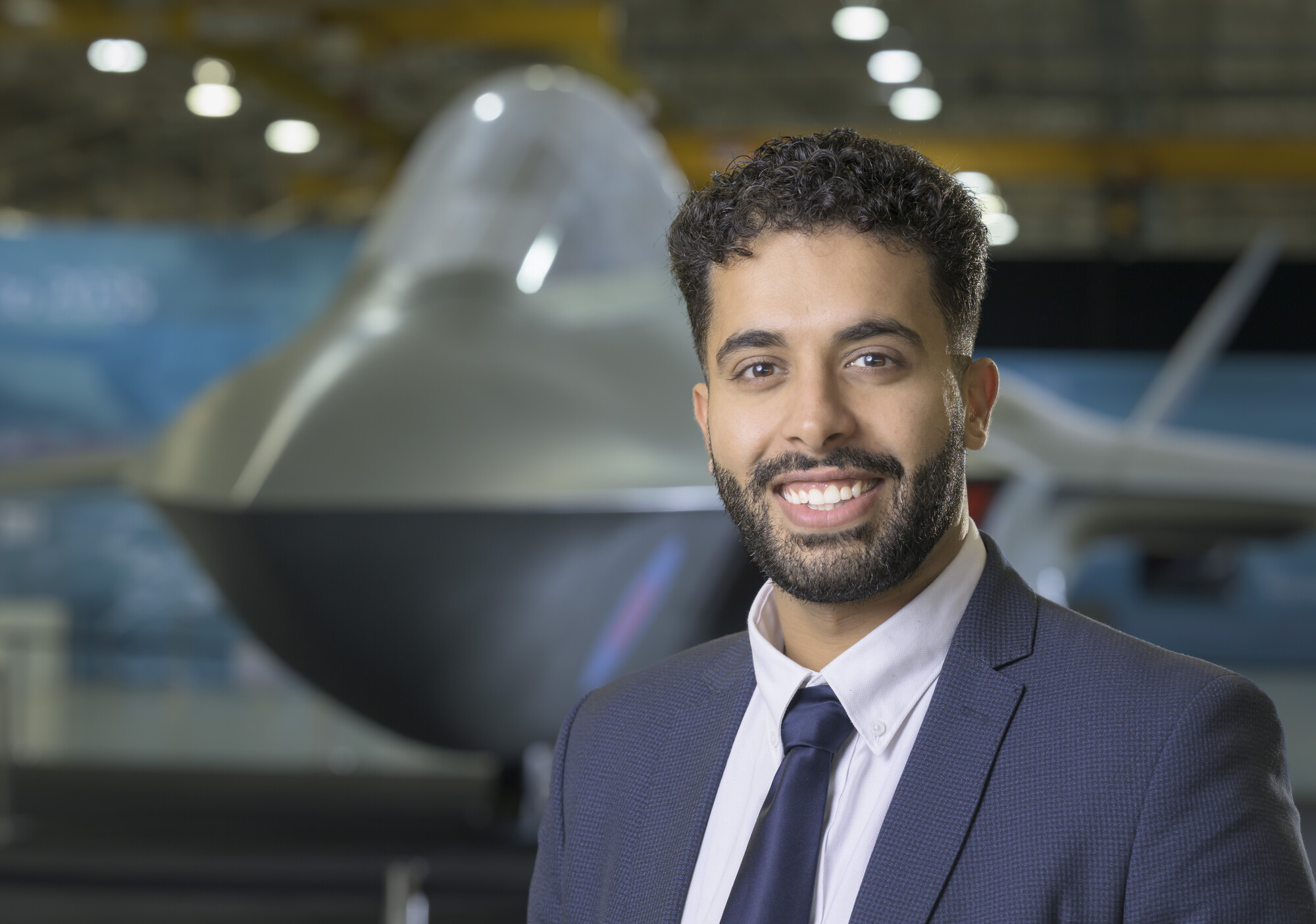 Rish looking at the camera smiling with the Tempest concept model in the background