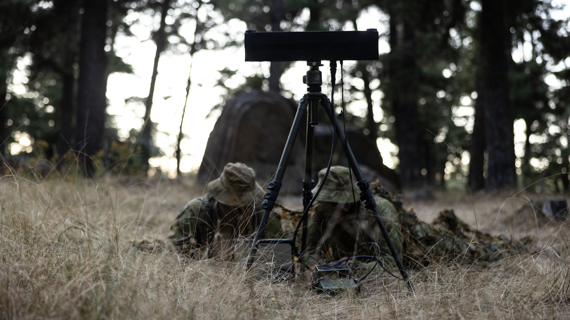 Two soldiers lying on the ground in a forest operating Mantlet Edge