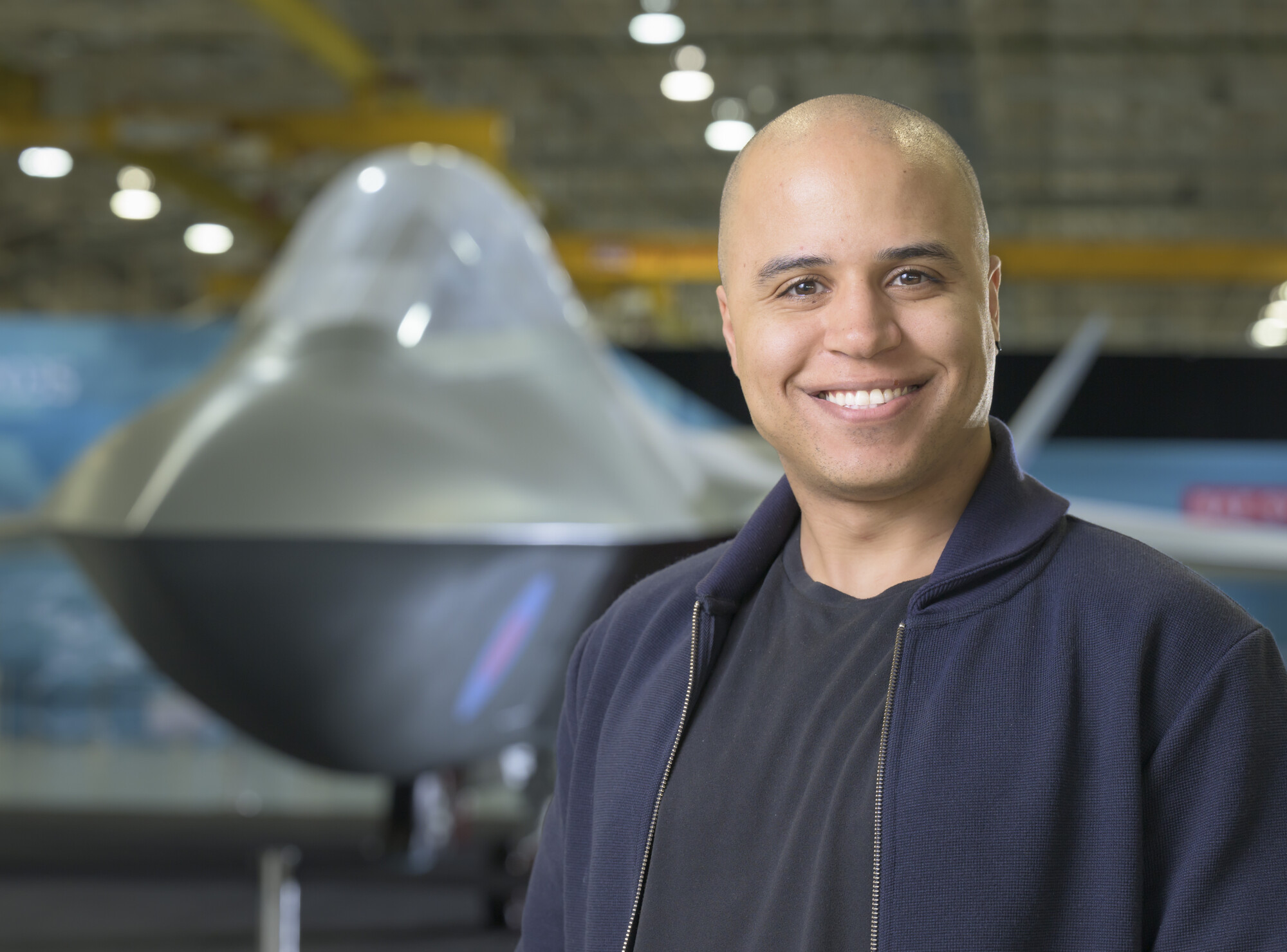 Lloyd looking at the camera smiling with the Tempest concept model in the background