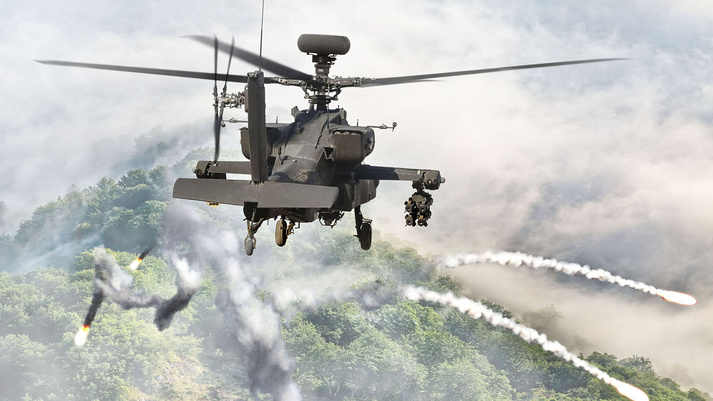 An Apache helicopter fires flares over a foggy, dense forest to counter IR and RF threats, showing the need for effective, small form full-spectrum self-protection. 