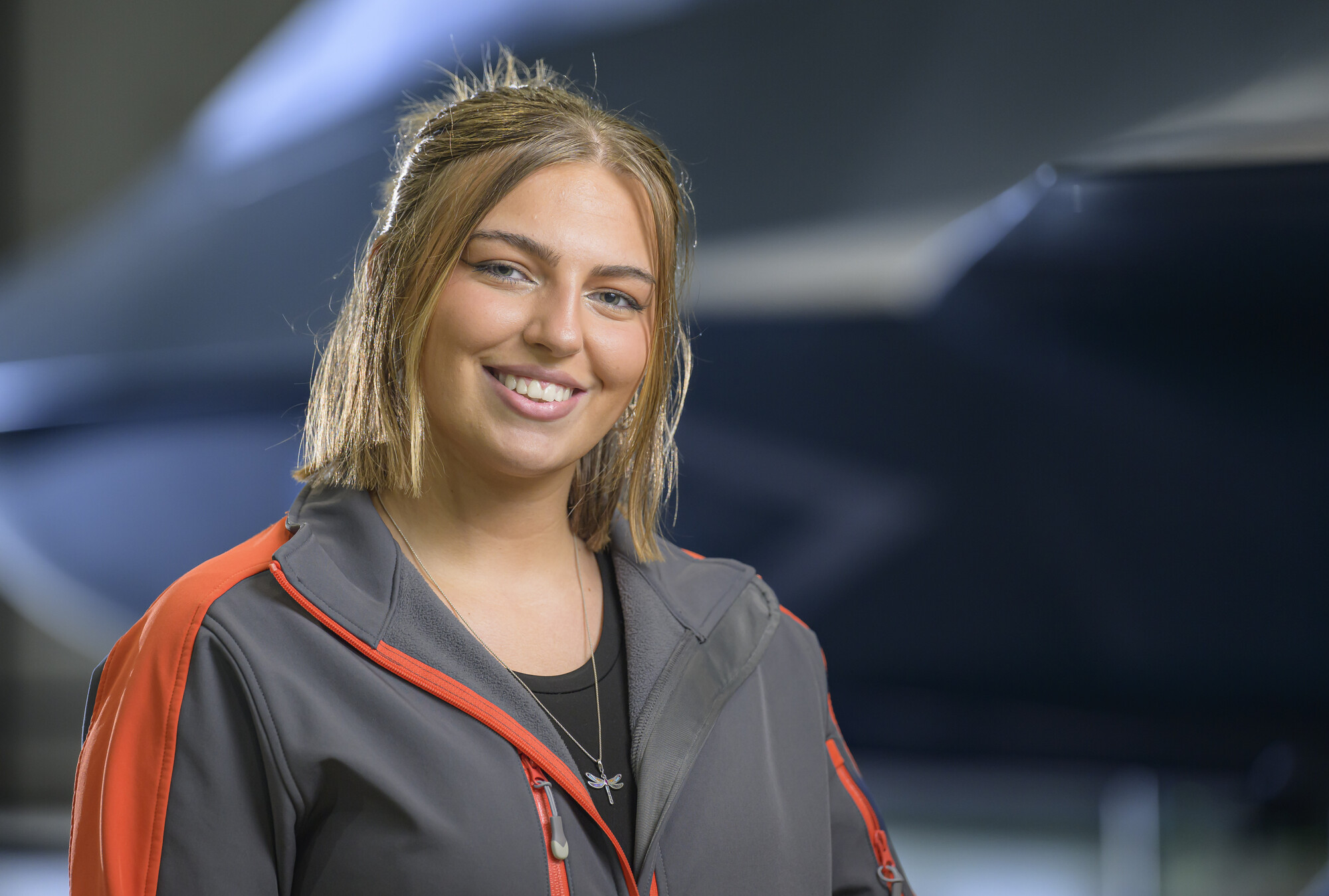 Carys looking at the camera smiling with the Tempest concept model in the background