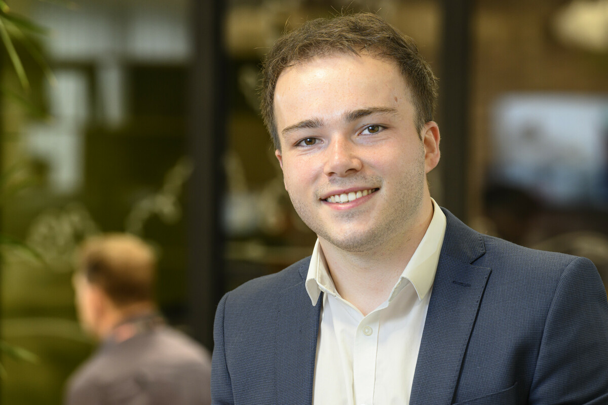 James sat in an office looking towards the camera and smiling