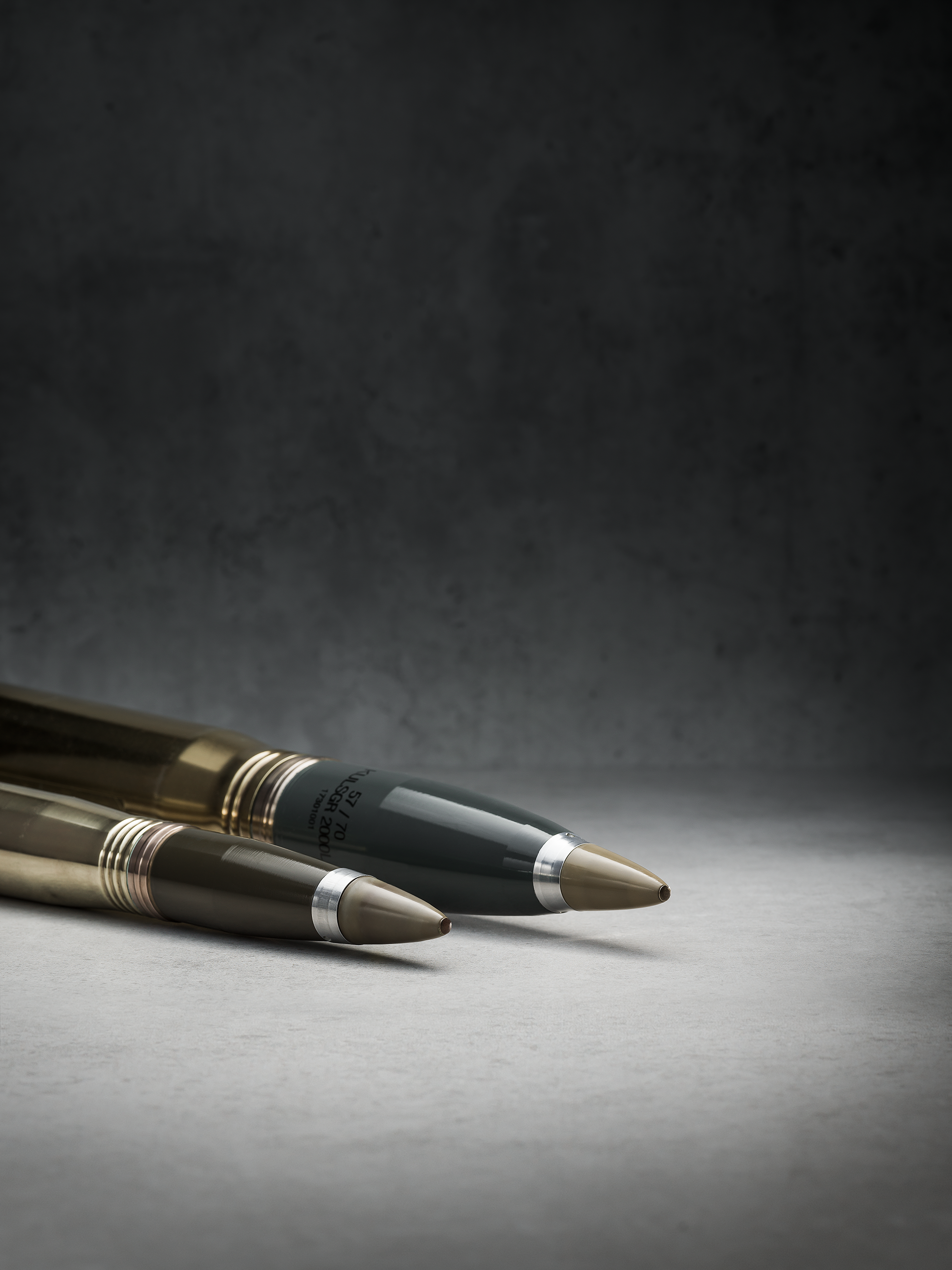 A close up of Bofors programmable ammunition 3P 40mm and 57mm on a gray background