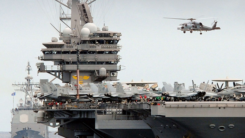 U.S. aircraft carrier with a full flight deck, helicopter above, and escort ships nearby. Our wide-band, high speed Common Data Link (CDL) radios provide integrated domains like these with interoperable data link communications to support every mission.